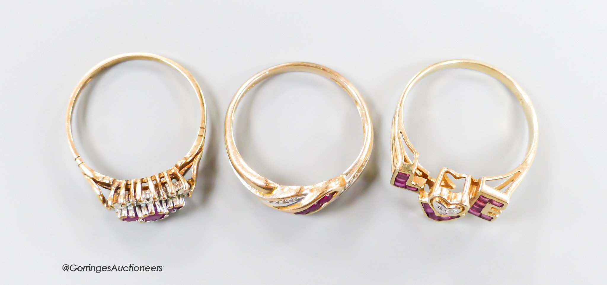 Three modern 9ct gold, ruby and diamond set dress rings including a 'Love' ring, size O, gross weight 5.7 grams.